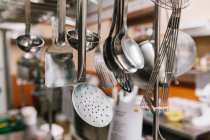 Close up view of ladles and spatulas hanging at restaurant kitchen — Stock Photo