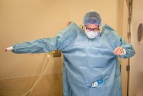 Portrait of doctor putting on surgery overall before operation — Stock Photo