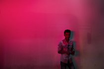 KAULA LUMPUR, MALASIA-26 MART, 2016: Giovane in camicia posa sullo sfondo della parete in luce al neon . — Foto stock