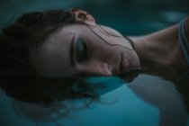 Половина лица женщины с закрытыми глазами в воде — стоковое фото