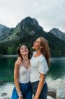 Обнимать девушек, позирующих на озере в горах — стоковое фото
