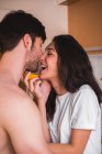 Cheerful couple with orange hugging and kissing. — Stock Photo