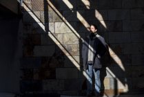 Junger Mann posiert erleuchtet von den Sonnenstrahlen im Schatten — Stockfoto