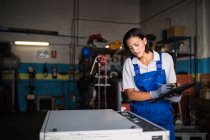 Female mechanic with clipboard checking machine status — Stock Photo