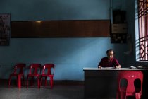 KAULA LUMPUR, MALASIA- 21 AVRIL 2016 : Homme mûr assis à table dans le hall près de la fenêtre avec des chaises le long du mur  . — Photo de stock