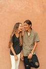 Portrait of laughing couple leaning brown wall. — Stock Photo