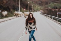 Brunette woman having fun on asphalt road on background of cows — Stock Photo