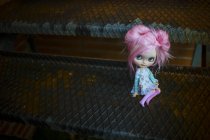 Vista de cerca de la muñeca moderna de pelo rosa sentada en escaleras de metal - foto de stock