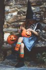 Girl in witch costume sitting on bench — Stock Photo