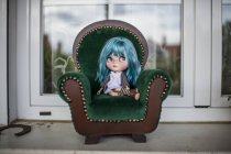 Vista de perto da boneca moderna de cabelos azuis sentada em uma poltrona pequena — Fotografia de Stock