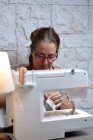 Female tailor in glasses needleworking at workplace — Stock Photo