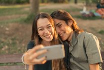 Retrato de una joven pareja sonriente tomando selfie con smartphone . - foto de stock