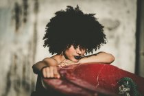 Girl with curly hair leaning on red construction and looking at camera — Stock Photo