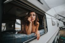 Frau in Unterwäsche blickt auf Fenster — Stockfoto
