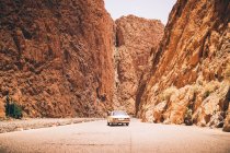 Брошенная желтая машина, стоящая в каньоне между двумя песчаными горами — стоковое фото