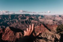 Crop hand stretching out to canyon hills landscape — Stock Photo