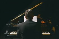 Задний вид человека в куртке, играющего на пианино — стоковое фото