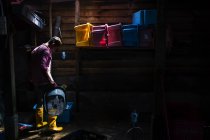 МАЛАЙЗИЯ - 9 апреля 2016 года: Вид сбоку человека в жёлтых резиновых сапогах внутри деревянного склада с коробкой . — стоковое фото