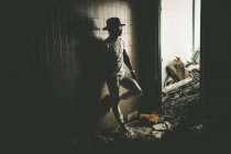 Stilvoller Mann lehnt an Wand in Zimmer mit Müllbergen. — Stockfoto
