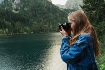 Girl taking photo of nature at lake in mountains. — Stock Photo