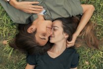 Vista dall'alto della coppia sdraiata sull'erba e abbracciata a occhi chiusi . — Foto stock