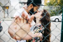 Besos pareja inclinada en valla - foto de stock