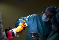 Retrato del médico colocando antiséptico en la pierna del paciente durante la operación quirúrgica . - foto de stock