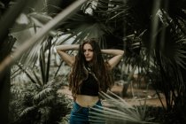 Bruna ragazza posa con le mani dietro la testa al giardino botanico — Foto stock