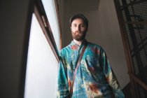 Bearded man in colorful shirt posing at stairs — Stock Photo