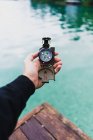 Crop male hand holding compass over water — Stock Photo