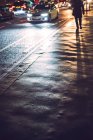 Headlight beams reflection and pedestrian shadow on wet road. — Stock Photo