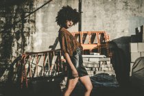 Young woman with afro wearing leather skirt posing at construction plant — Stock Photo