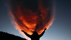 Silueta chica agarrando rojo nube en el cielo - foto de stock