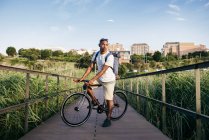 Человек позирует с велосипедом на набережной — стоковое фото
