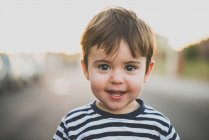 Portrait de charmant petit garçon aux yeux bruns et aux cheveux regardant la caméra avec le sourire . — Photo de stock