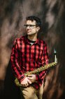 Музикант в окулярах стоїть з саксофоном — стокове фото