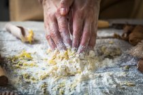 Visão de perto de mãos que amassam ingredientes na massa de farinha — Fotografia de Stock