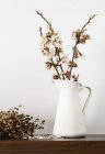 Fresh cut blooming sprigs in vase on shelf — Stock Photo