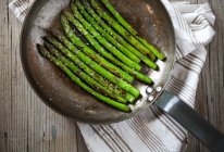 Fried asparagus sprouts in rustic pan — Stock Photo