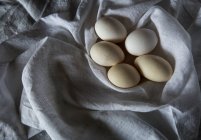 Directly above white eggs on white rural towel — Stock Photo