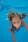 Niño nadando en la piscina y mirando a la cámara - foto de stock