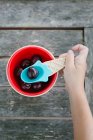 Hand of little girl taking cherry with spoon from bowl — Stock Photo