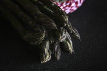 Fresh green asparagus on black — Stock Photo