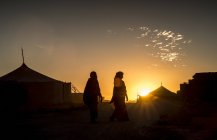 Silhouette di due persone che camminano al tramonto — Foto stock