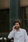 Porträt eines selbstbewussten Geschäftsmannes im weißen Hemd, der in der Großstadt mit dem Smartphone spricht — Stockfoto
