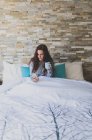 Mädchen liegt auf Bett und benutzt Smartphone — Stockfoto