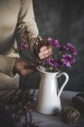Imagen de la floristería femenina colocando flor en jarrón de cerámica en la mesa - foto de stock