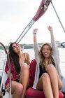 Porträt zweier fröhlicher Frauen, die auf einem Segelboot-Deck vor dem Hintergrund des Ozeans posieren. — Stockfoto