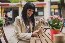 Женщина со смартфоном на террасе кафе — стоковое фото
