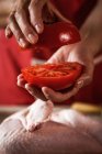 Nahaufnahme weiblicher Hände, die frische halbierte Tomaten zur Zubereitung von Hühnchen halten — Stockfoto